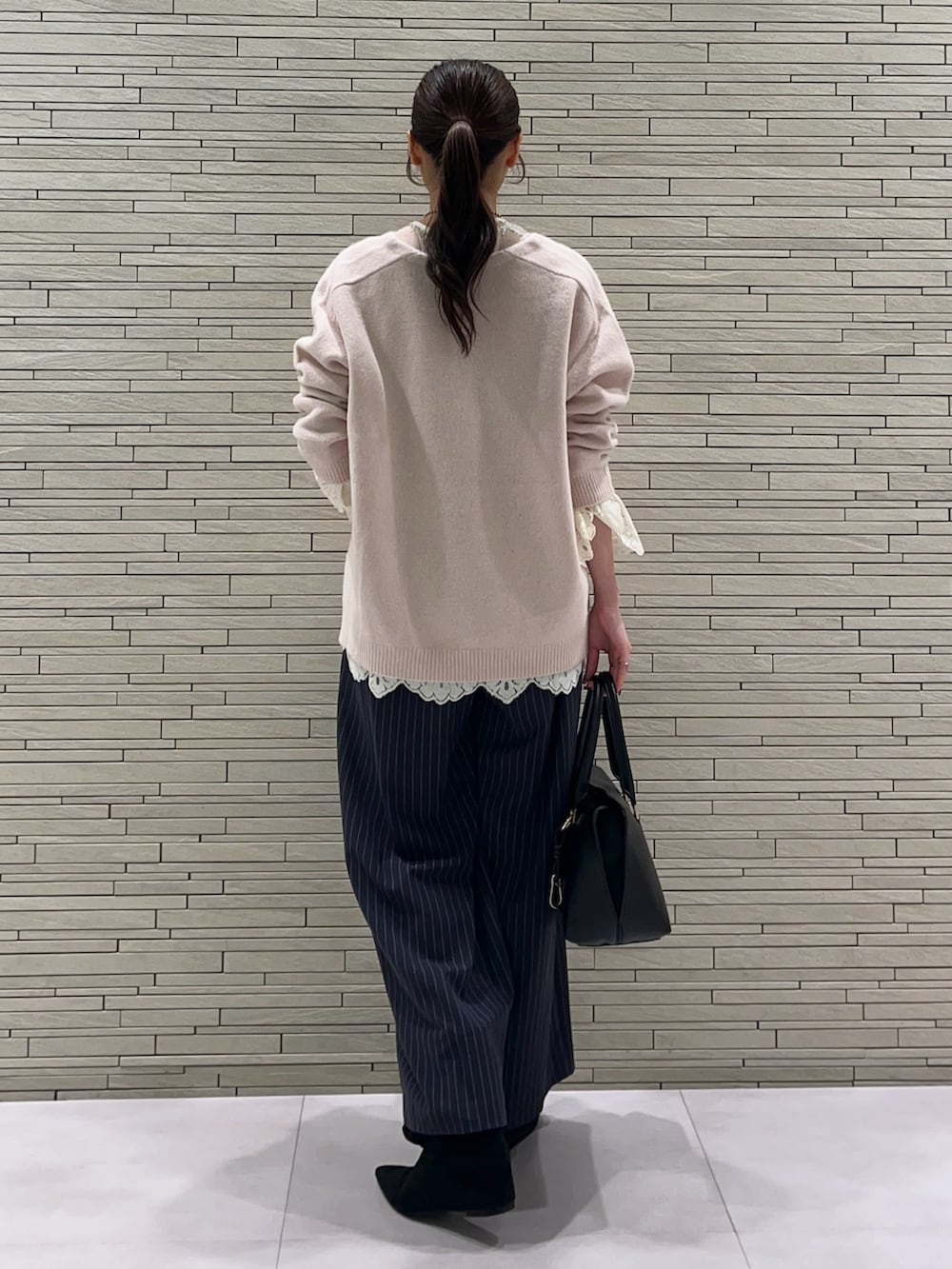 ピンク系のニット/セーター、ホワイト系のTシャツ/カットソー、ブルー系のスラックスを着用したレディースの秋コーディネートの4枚目の写真