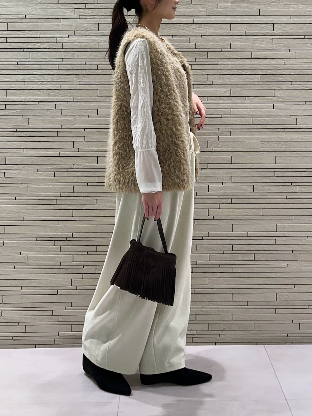 ホワイト系のその他パンツ、ブラック系のその他シューズ、ベージュ系のベストを着用したレディースの秋コーディネートの2枚目の写真