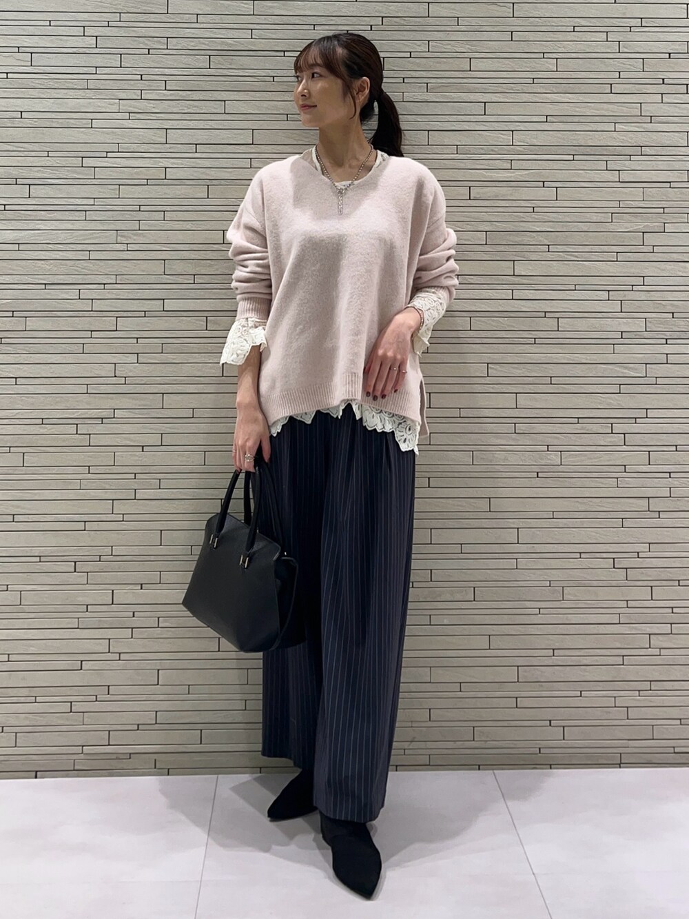 ピンク系のニット/セーター、ホワイト系のTシャツ/カットソー、ブルー系のスラックスを着用したレディースの秋コーディネートの5枚目の写真