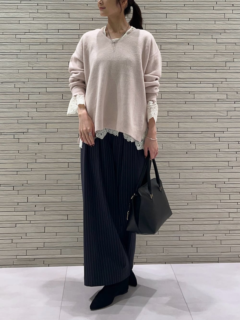 ピンク系のニット/セーター、ホワイト系のTシャツ/カットソー、ブルー系のスラックスを着用したレディースの秋コーディネートの3枚目の写真