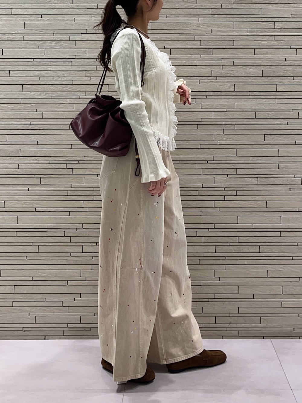 ホワイト系のカーディガン/ボレロ、ベージュ系のその他パンツ、レッド系のトートバッグを着用したレディースの秋コーディネートの4枚目の写真