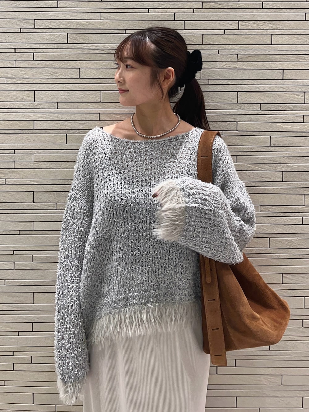 グレー系のニット/セーター、ベージュ系のスカート、シルバー系のネックレスを着用したレディースの秋コーディネートの5枚目の写真