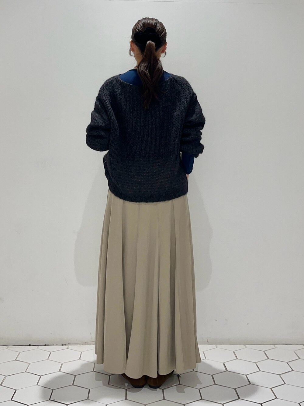 グレー系のニット/セーター、ブルー系のTシャツ/カットソー、ベージュ系のスカートを着用したレディースの秋コーディネートの5枚目の写真