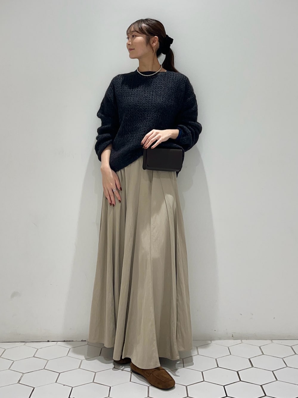 グレー系のニット/セーター、ブルー系のTシャツ/カットソー、ベージュ系のスカートを着用したレディースの秋コーディネートの2枚目の写真