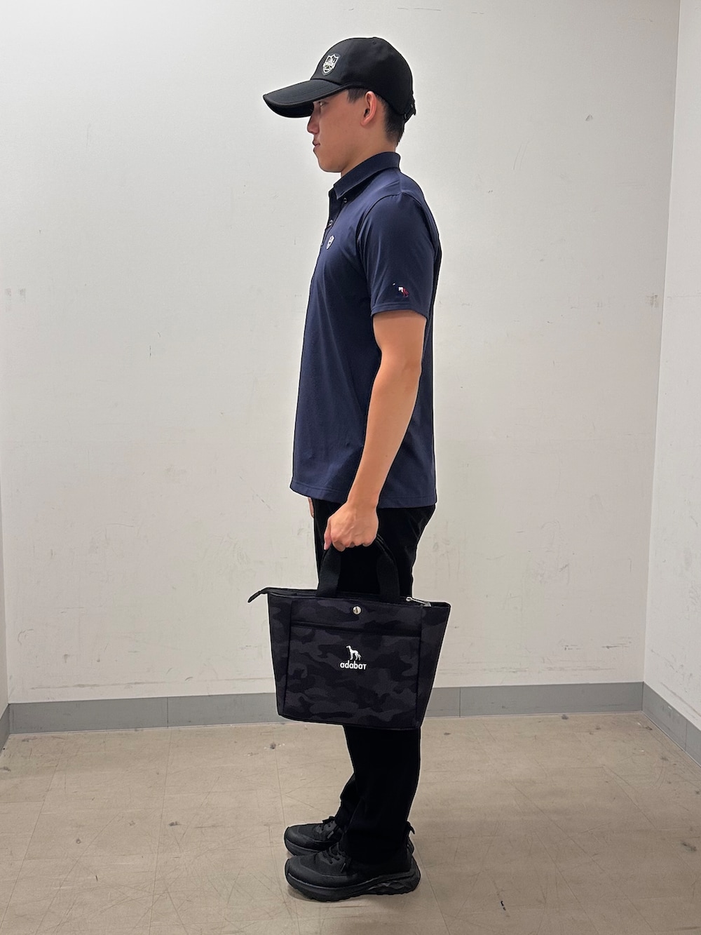 ブルー系のポロシャツ、ブラック系のその他パンツ、ブラック系のトートバッグを着用したメンズの夏コーディネートの2枚目の写真
