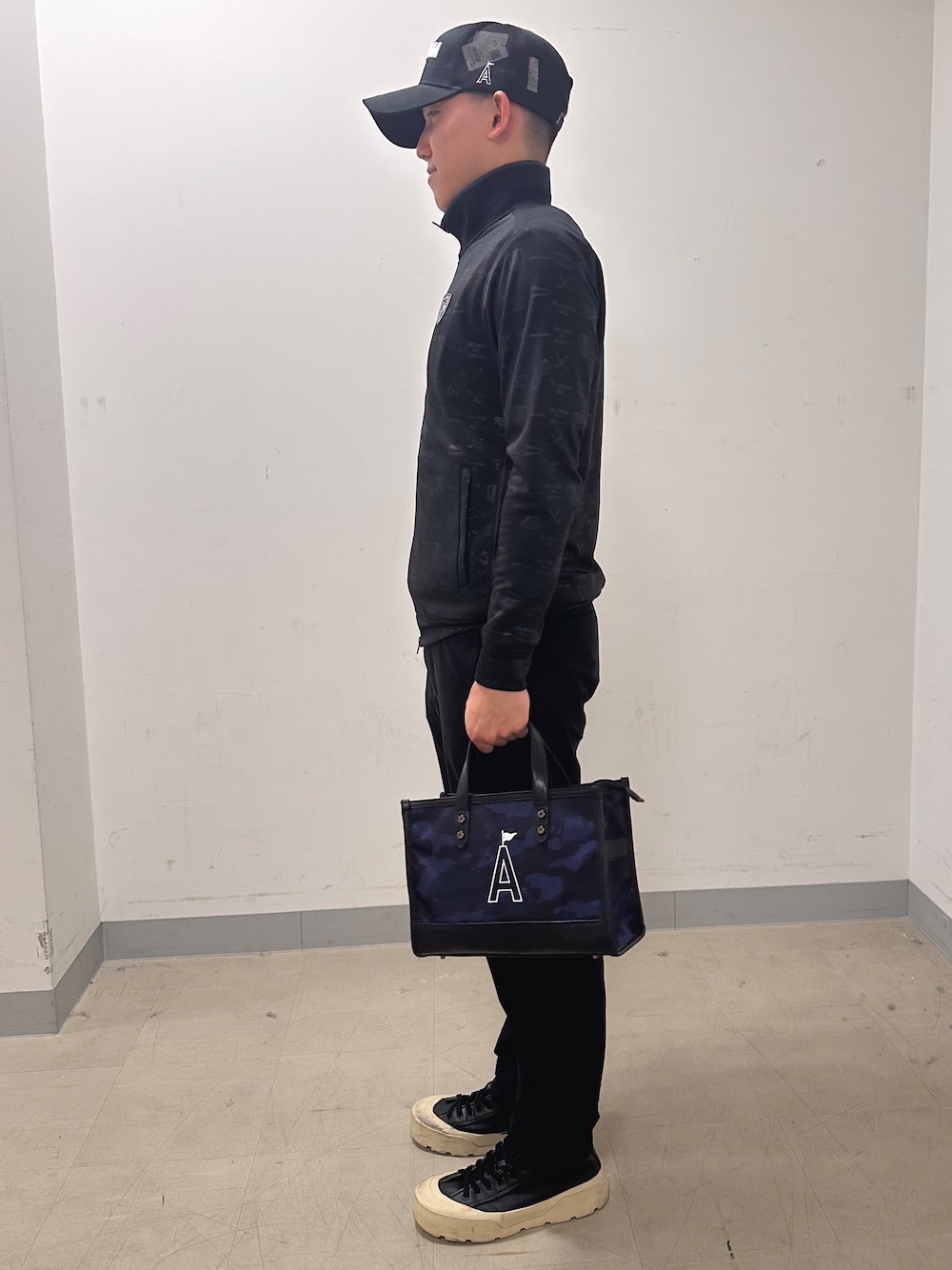 ブラック系のブルゾン、ブラック系のその他パンツ、ブルー系のトートバッグを着用したメンズの夏コーディネートの2枚目の写真