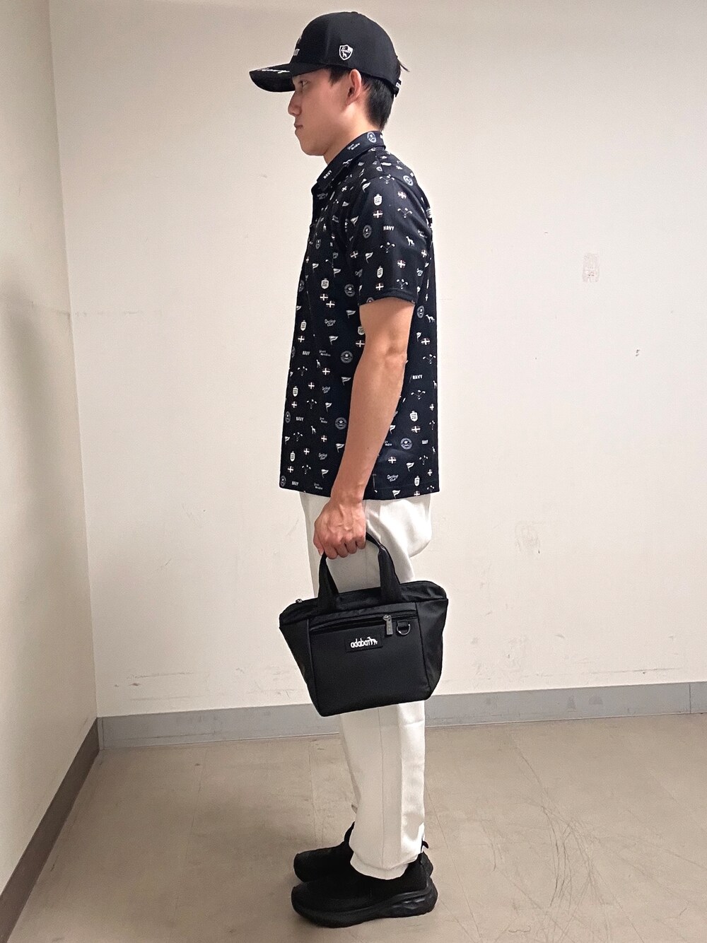 ブルー系のポロシャツ、グレー系のその他パンツ、ブラック系のキャップを着用したメンズの夏コーディネートの2枚目の写真