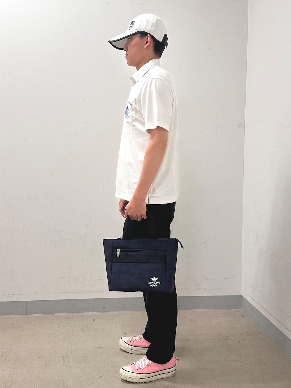 ホワイト系のポロシャツ、ブラック系のその他パンツ、ブルー系のトートバッグを着用したメンズの夏コーディネートの2枚目の写真