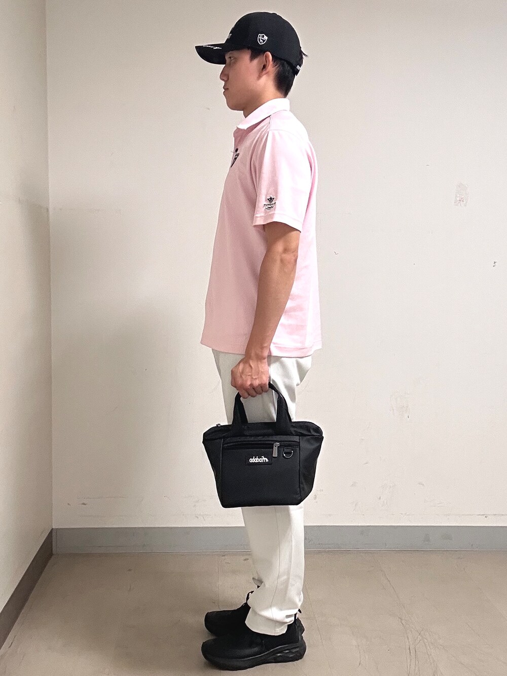 ピンク系のポロシャツ、グレー系のその他パンツ、ブラック系のキャップを着用したメンズの夏コーディネートの2枚目の写真