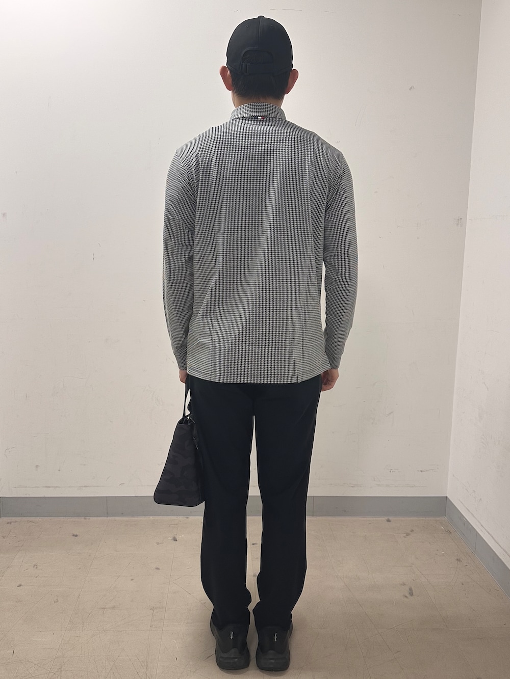 ホワイト系のポロシャツ、ブラック系のその他パンツ、ブラック系のトートバッグを着用したメンズの秋コーディネートの3枚目の写真