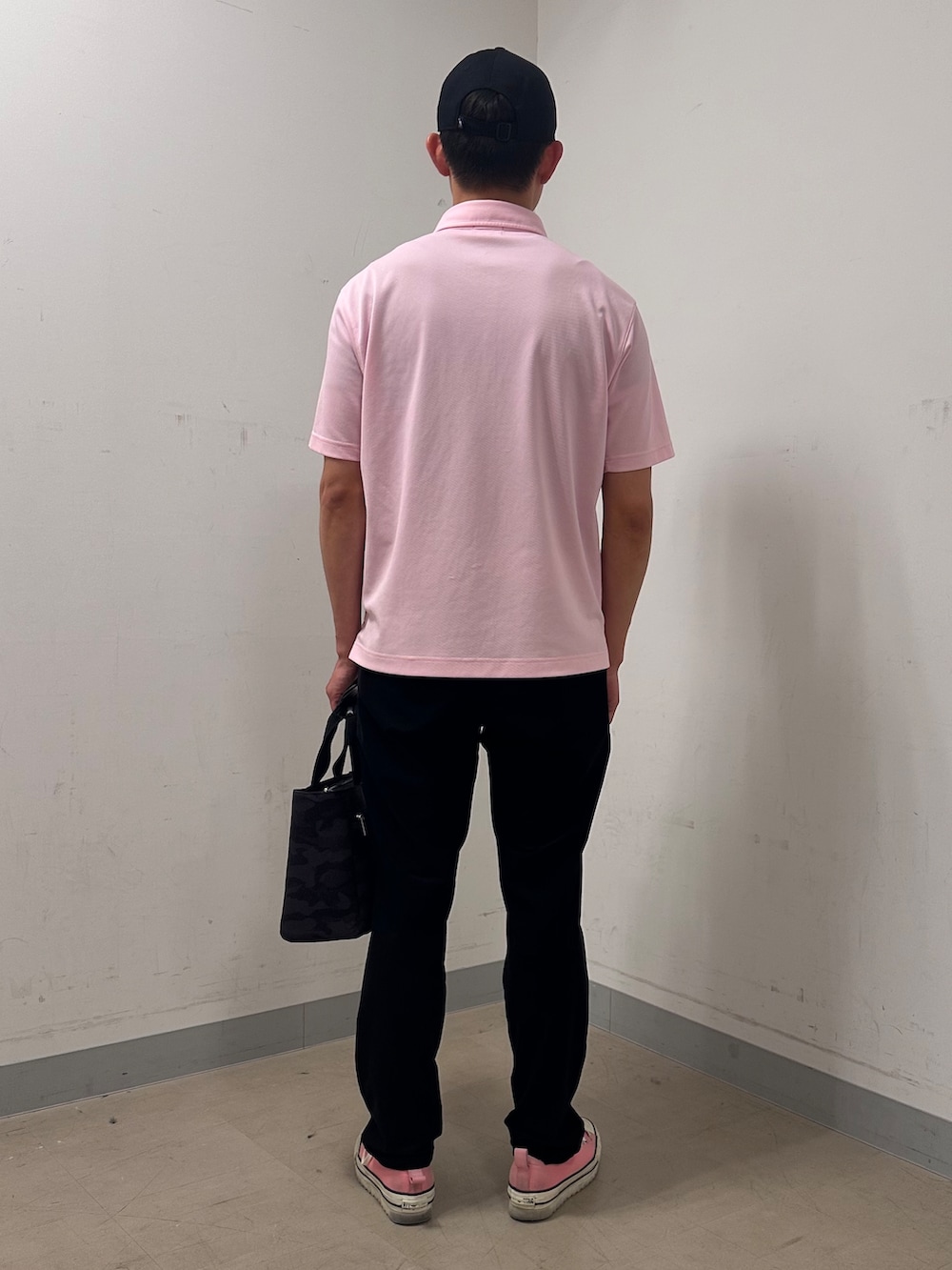 ピンク系のポロシャツ、ブラック系のその他パンツ、ブラック系のトートバッグを着用したメンズの夏コーディネートの3枚目の写真