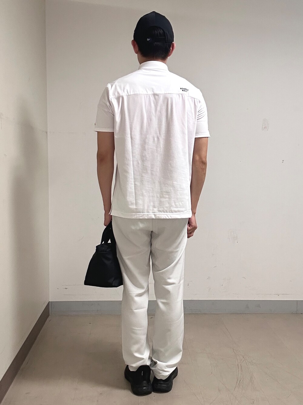 ホワイト系のポロシャツ、グレー系のその他パンツ、ブラック系のキャップを着用したメンズの夏コーディネートの3枚目の写真