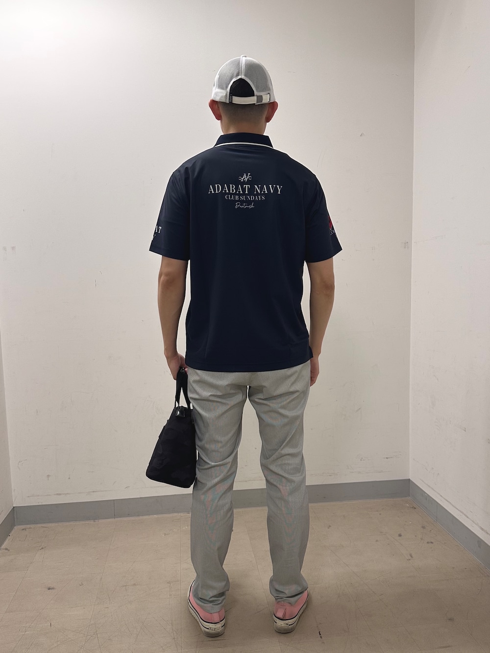 ブルー系のポロシャツ、グレー系のその他パンツ、ブラック系のトートバッグを着用したメンズの夏コーディネートの3枚目の写真