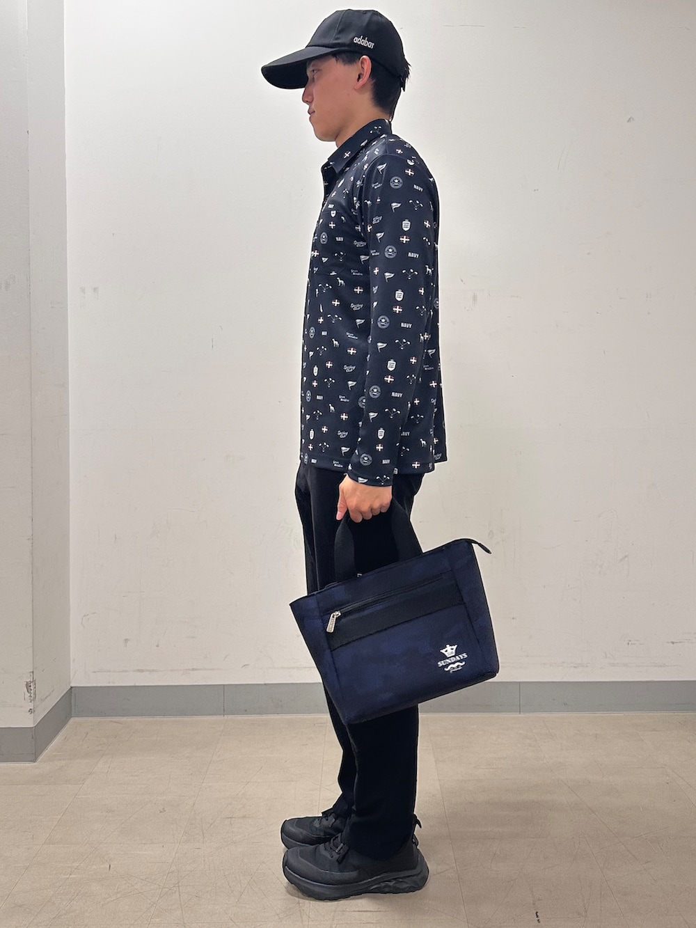 ブルー系のポロシャツ、ブラック系のその他パンツ、ブルー系のトートバッグを着用したメンズの秋コーディネートの2枚目の写真