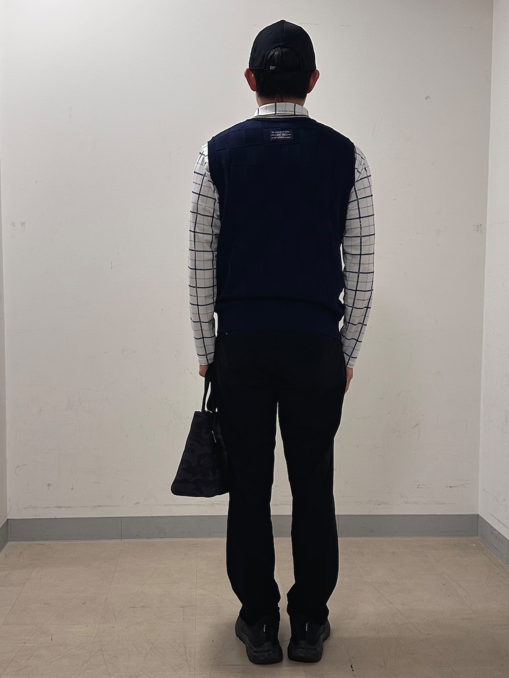 ホワイト系のポロシャツ、グレー系のベスト、ブラック系のその他パンツを着用したメンズの秋コーディネートの3枚目の写真