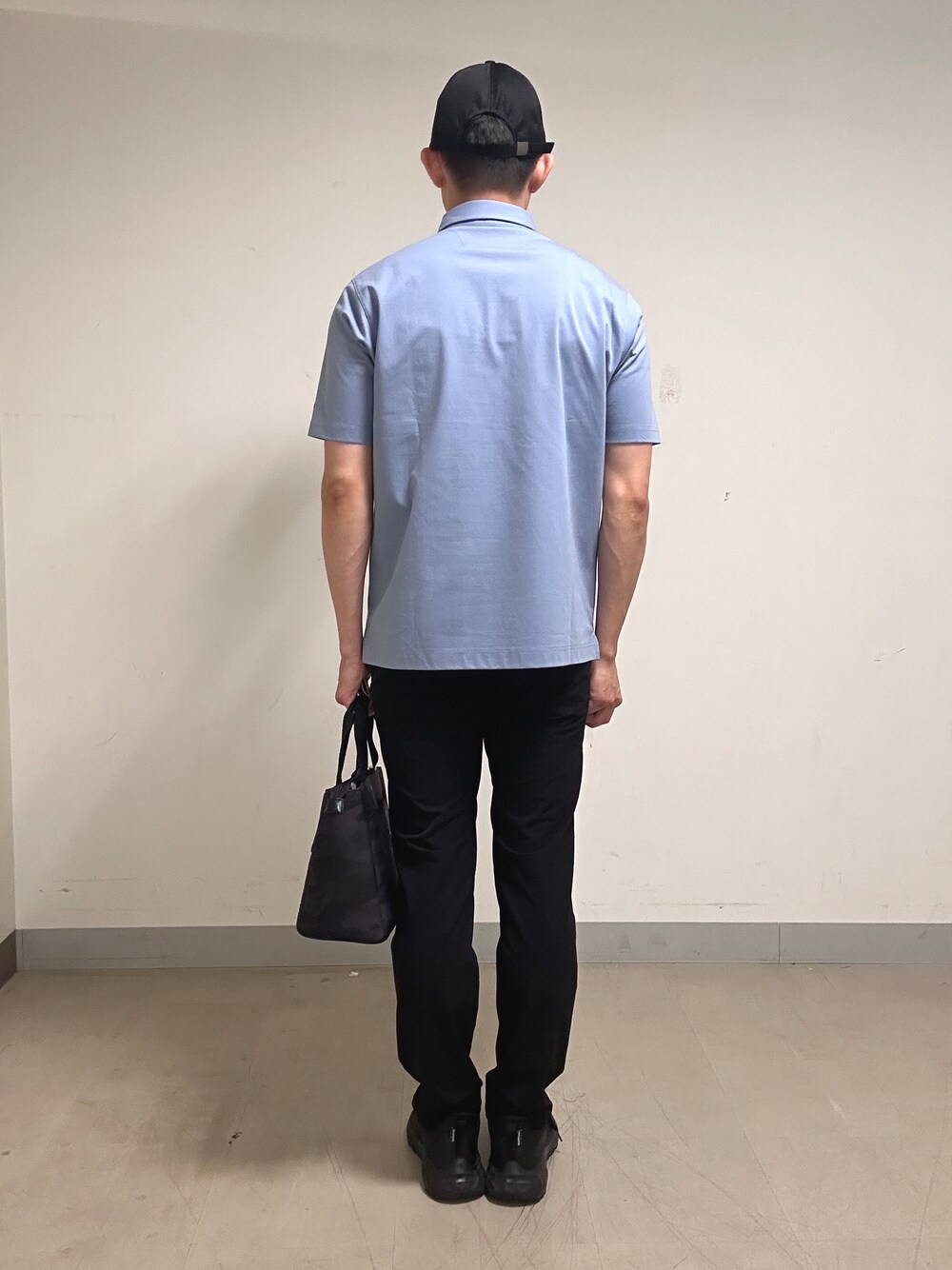 ブルー系のポロシャツ、グレー系のその他パンツ、ブラック系のトートバッグを着用したメンズの夏コーディネートの3枚目の写真