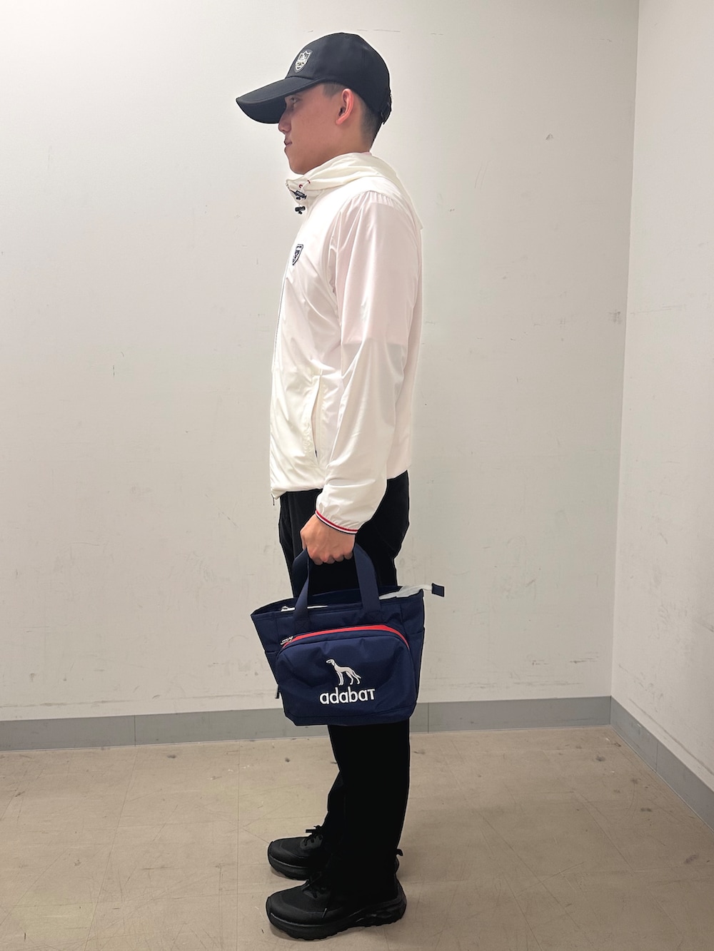 ホワイト系のブルゾン、ブラック系のその他パンツ、ブルー系のトートバッグを着用したメンズの夏コーディネートの2枚目の写真