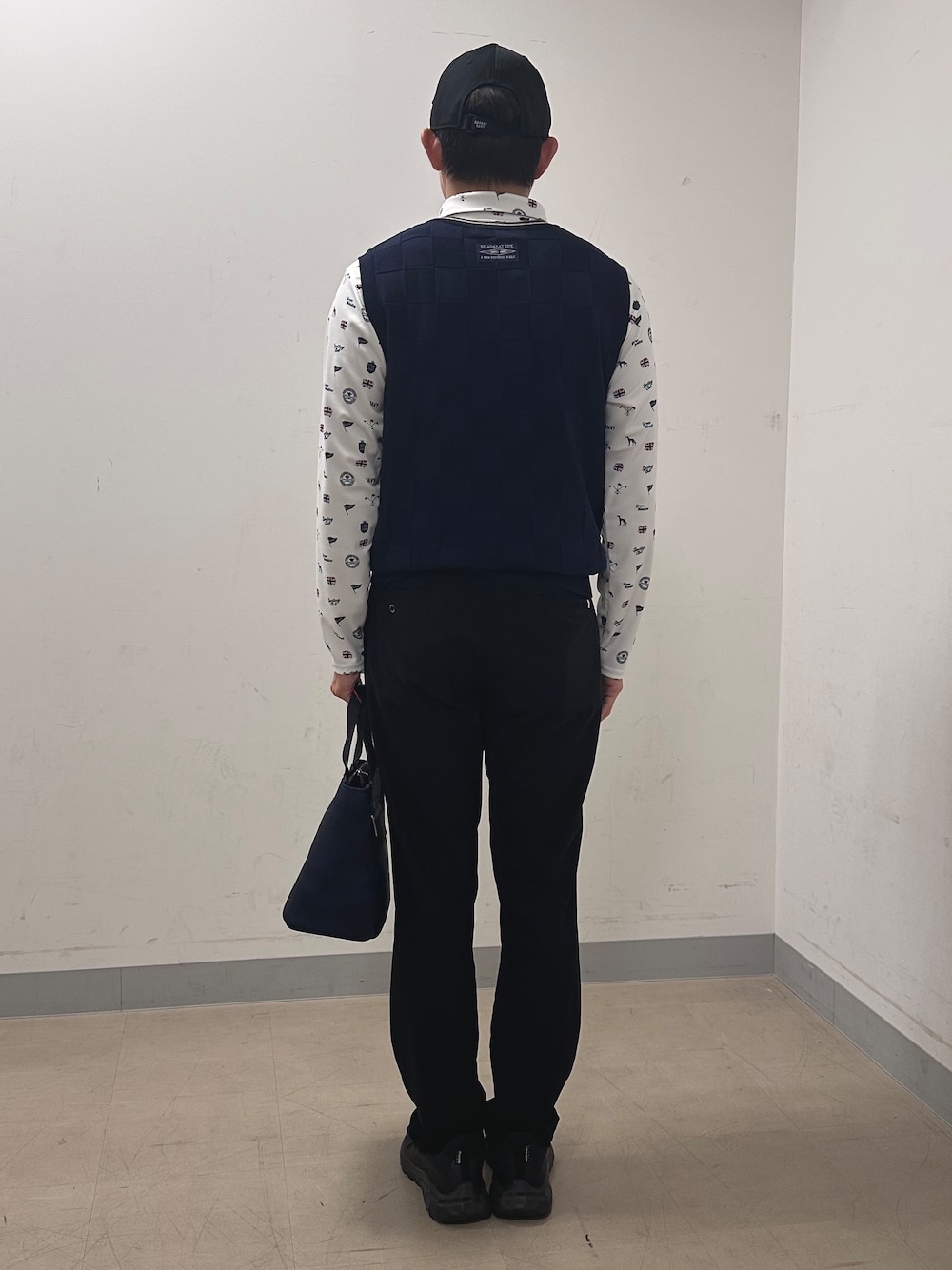 ホワイト系のポロシャツ、ブラック系のその他パンツ、ブルー系のトートバッグを着用したメンズの秋コーディネートの3枚目の写真