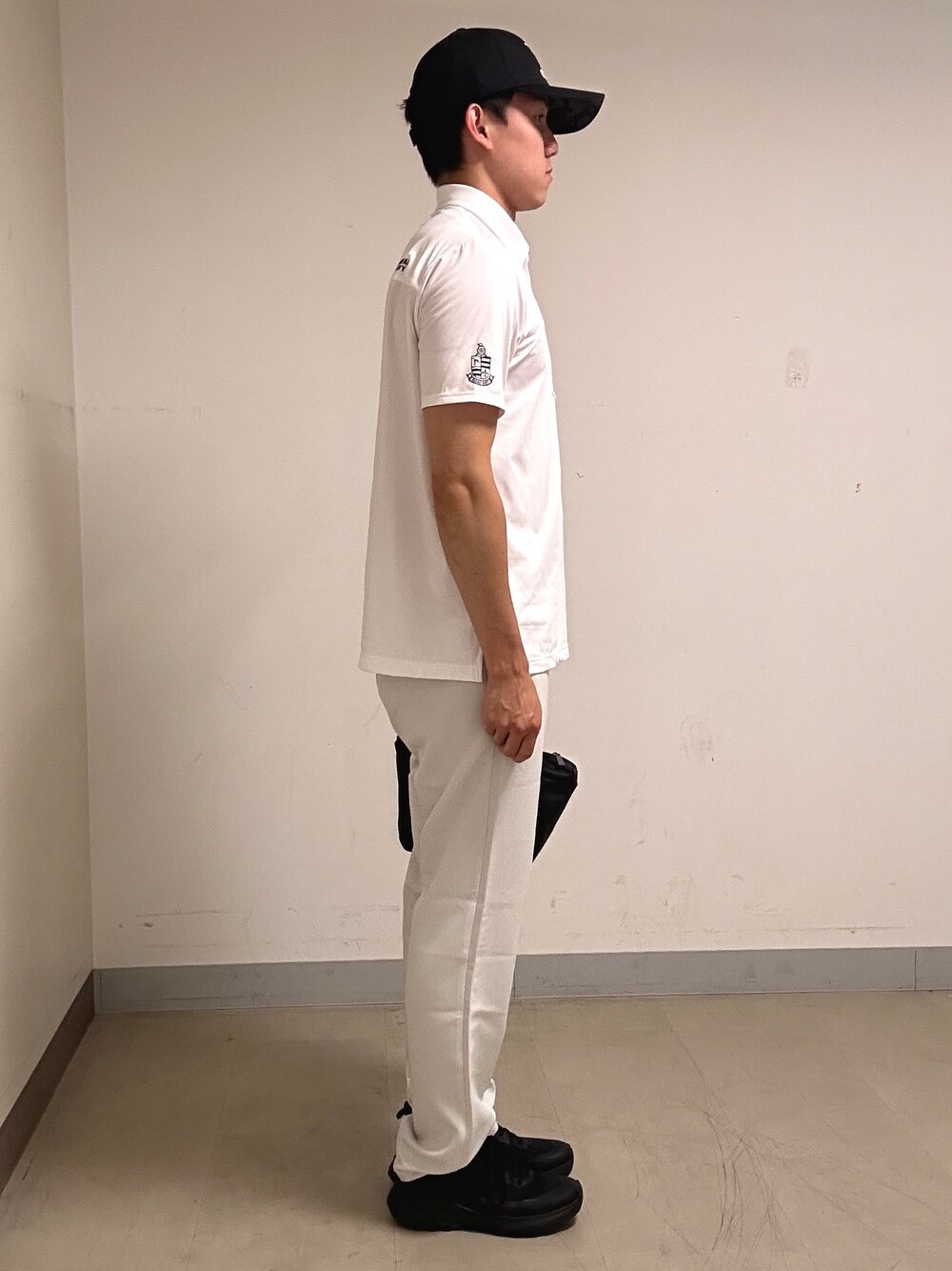 ホワイト系のポロシャツ、グレー系のその他パンツ、ブラック系のキャップを着用したメンズの夏コーディネートの4枚目の写真