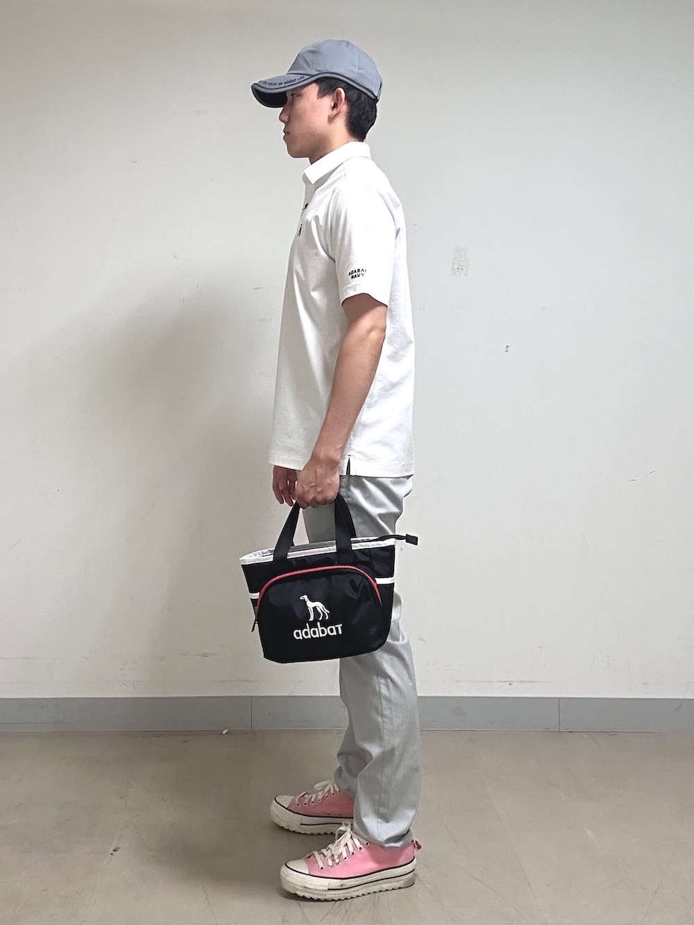 ホワイト系のポロシャツ、グレー系のその他パンツ、ブラック系のトートバッグを着用したメンズの夏コーディネートの3枚目の写真