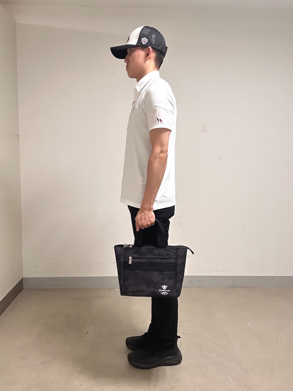 ホワイト系のポロシャツ、グレー系のその他パンツ、ブラック系のトートバッグを着用したメンズの夏コーディネートの2枚目の写真