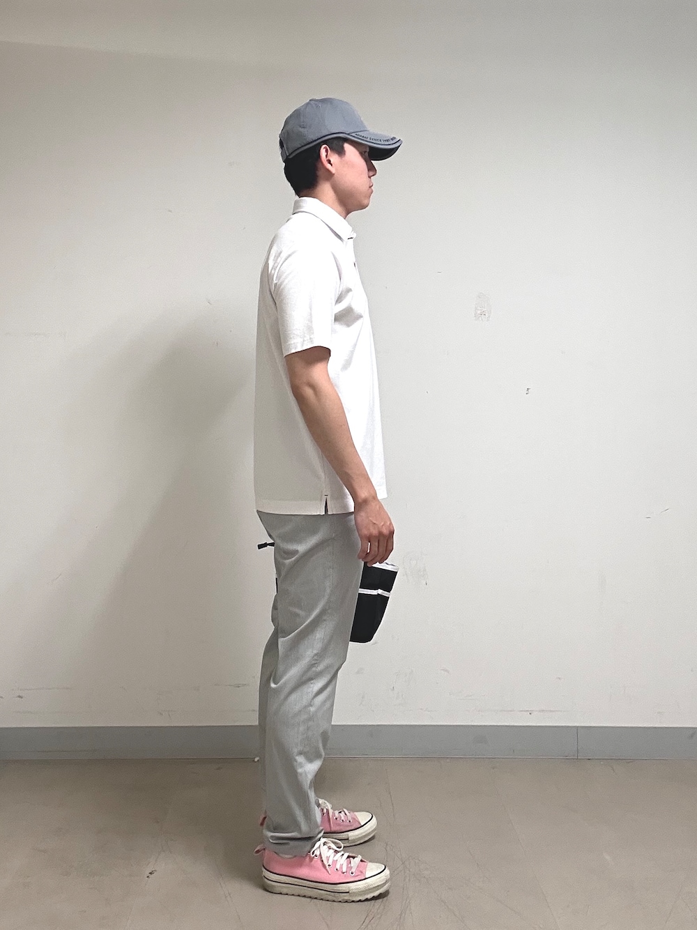 ホワイト系のポロシャツ、グレー系のその他パンツ、ブラック系のトートバッグを着用したメンズの夏コーディネートの2枚目の写真