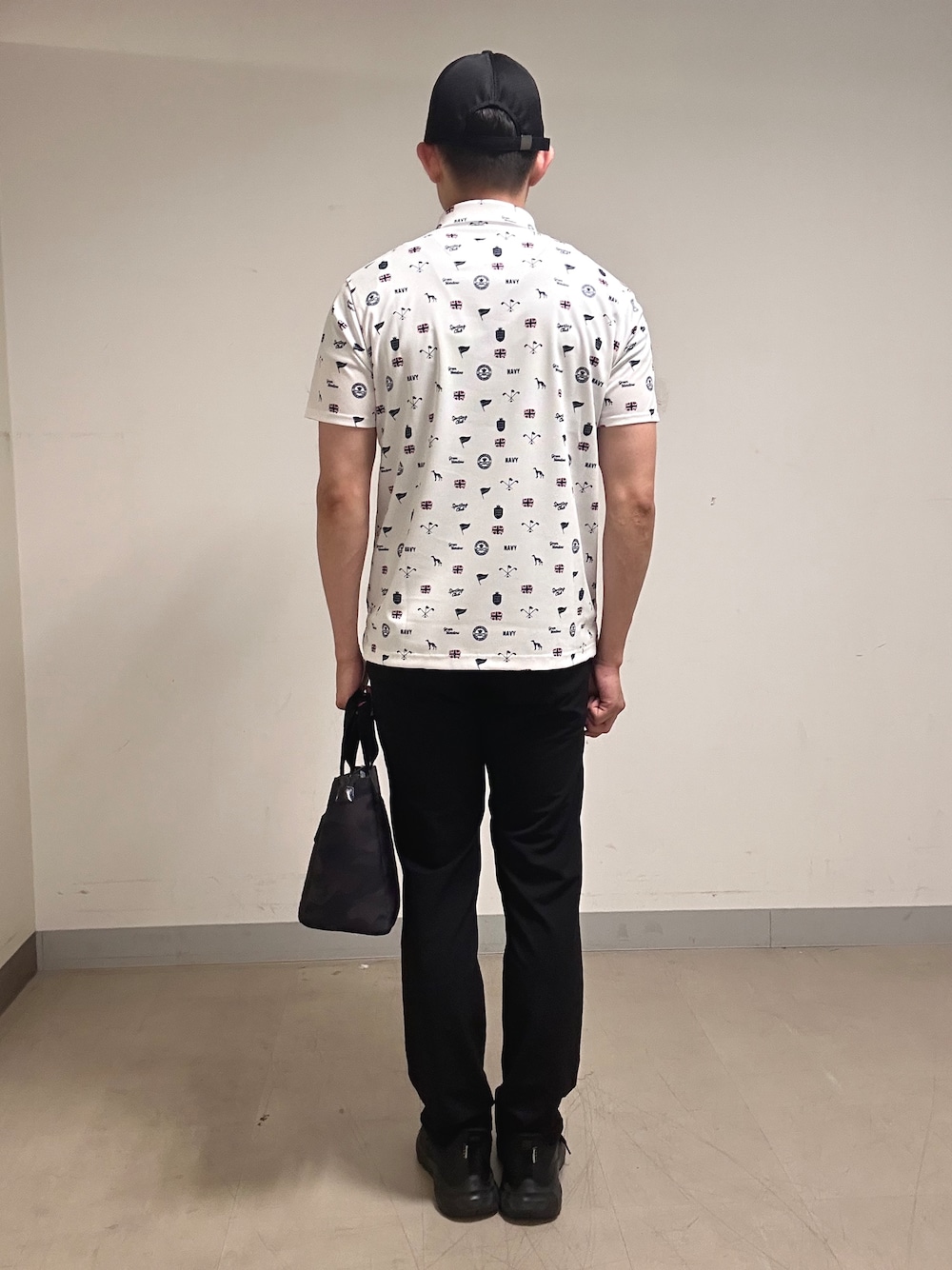 ホワイト系のポロシャツ、グレー系のその他パンツ、ブラック系のトートバッグを着用したメンズの夏コーディネートの3枚目の写真