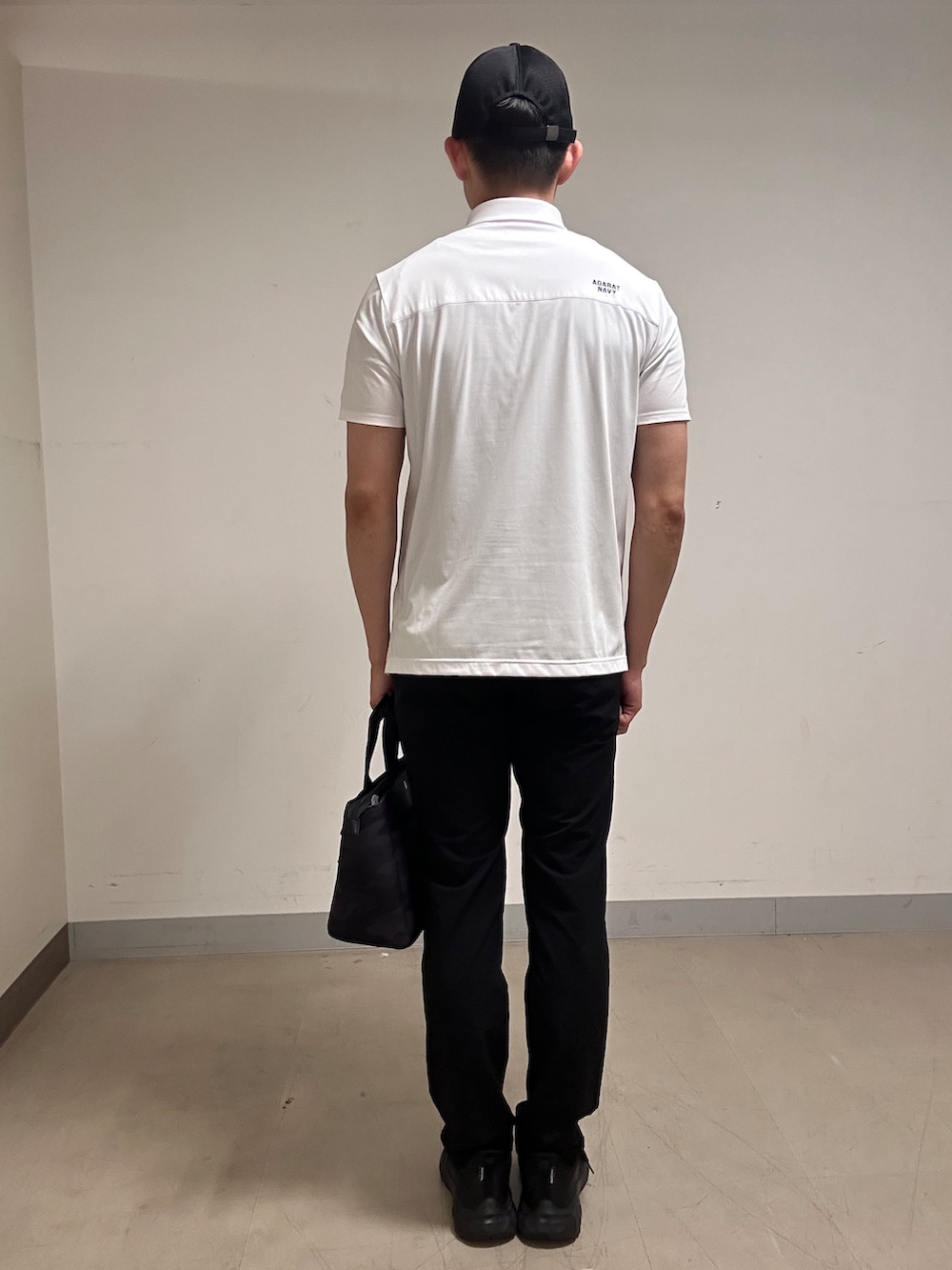 ホワイト系のポロシャツ、グレー系のその他パンツ、ブラック系のトートバッグを着用したメンズの夏コーディネートの3枚目の写真