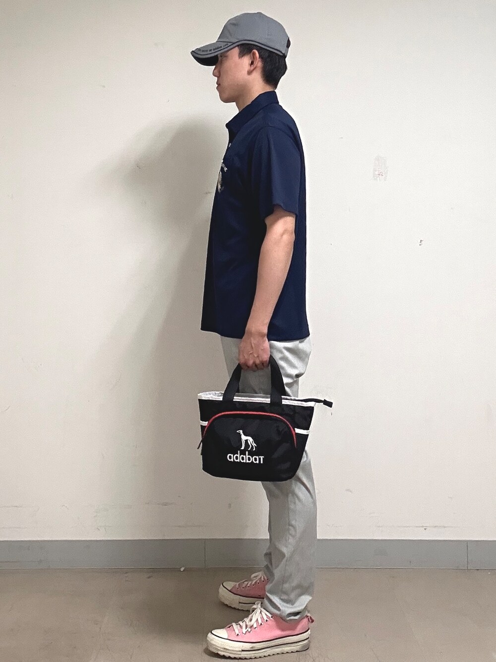 ブルー系のポロシャツ、グレー系のその他パンツ、ブラック系のトートバッグを着用したメンズの夏コーディネートの2枚目の写真