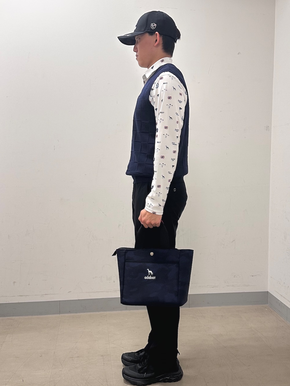 ホワイト系のポロシャツ、ブラック系のその他パンツ、ブルー系のトートバッグを着用したメンズの秋コーディネートの2枚目の写真