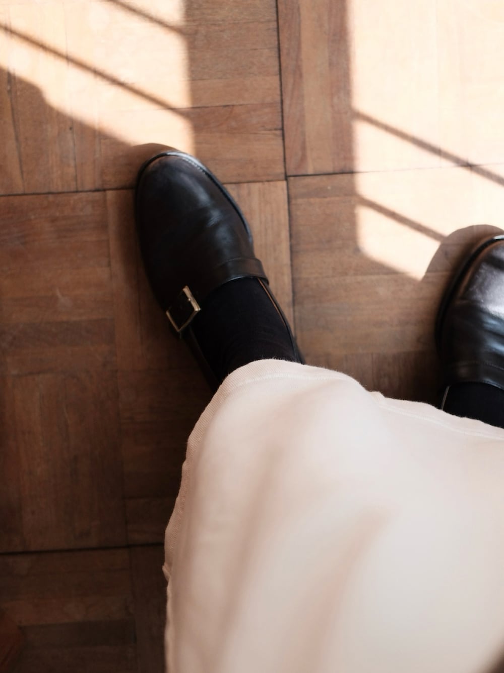 ホワイト系のスカート、ベージュ系のニット/セーター、ブラック系のドレスシューズを着用したレディースの春コーディネートの3枚目の写真