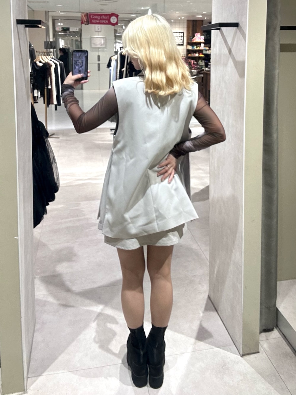 ブラック系のブーツ、ベージュ系のスカート、ベージュ系のベストを着用したレディースの春コーディネートの3枚目の写真