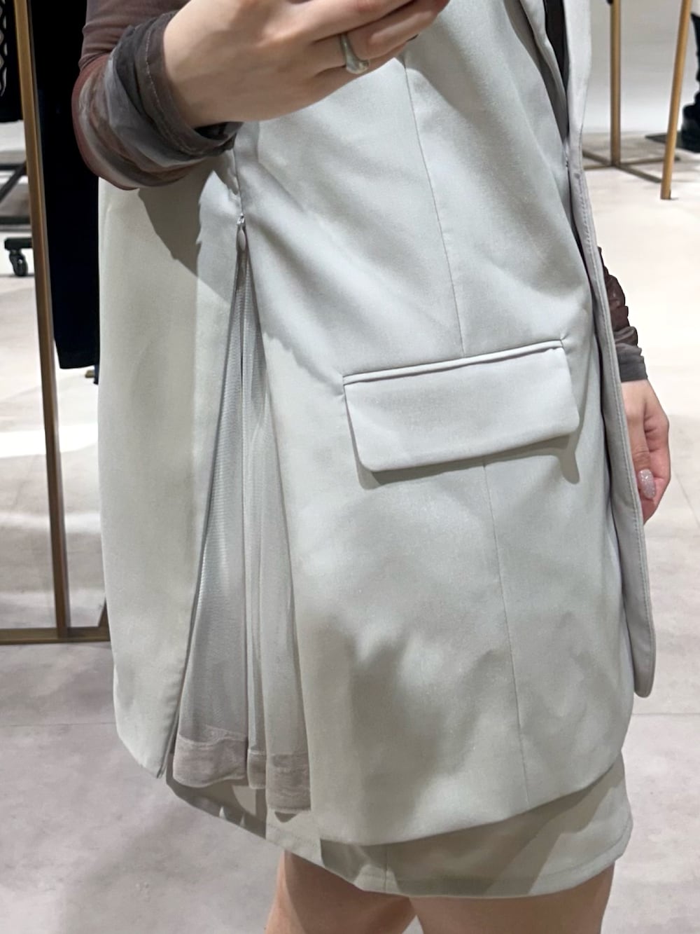 ブラック系のブーツ、ベージュ系のスカート、ベージュ系のベストを着用したレディースの春コーディネートの4枚目の写真