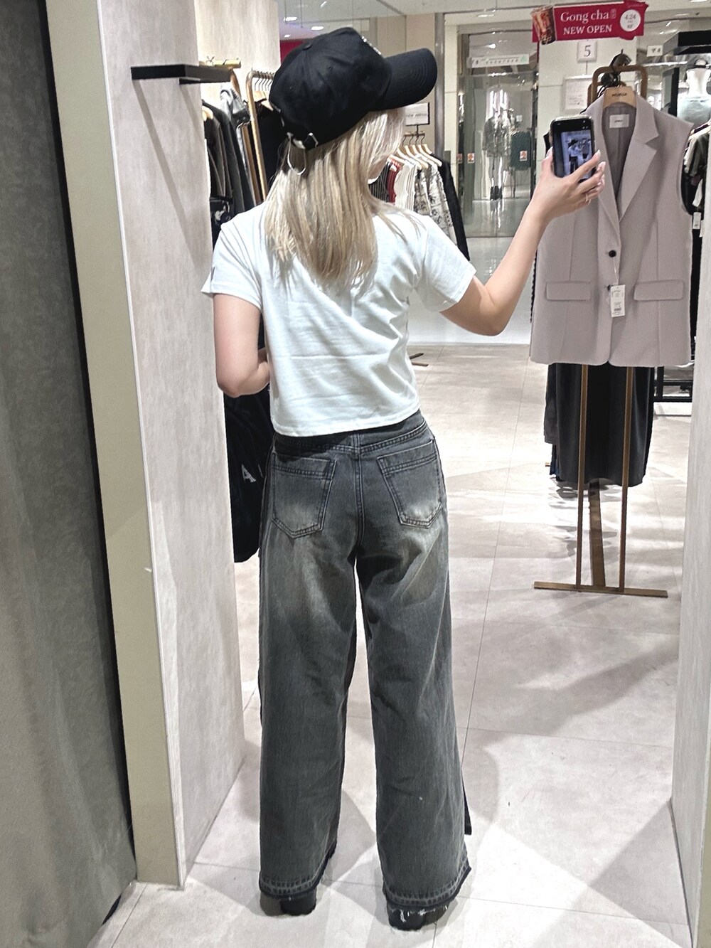 ブラック系のデニムパンツ、ブラック系のブーツ、ホワイト系のTシャツ/カットソーを着用したレディースの春コーディネートの3枚目の写真