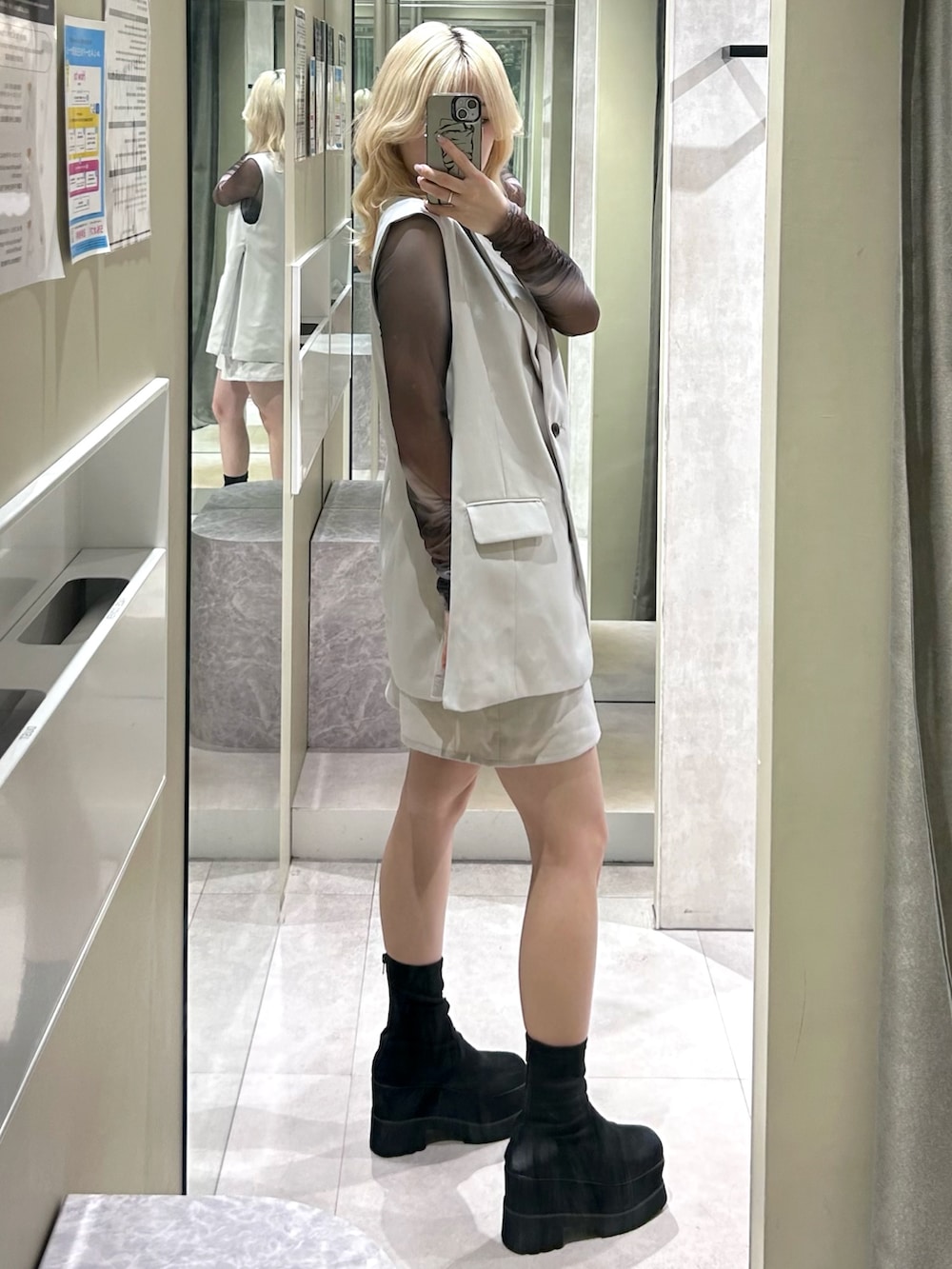 ブラック系のブーツ、ベージュ系のスカート、ベージュ系のベストを着用したレディースの春コーディネートの2枚目の写真