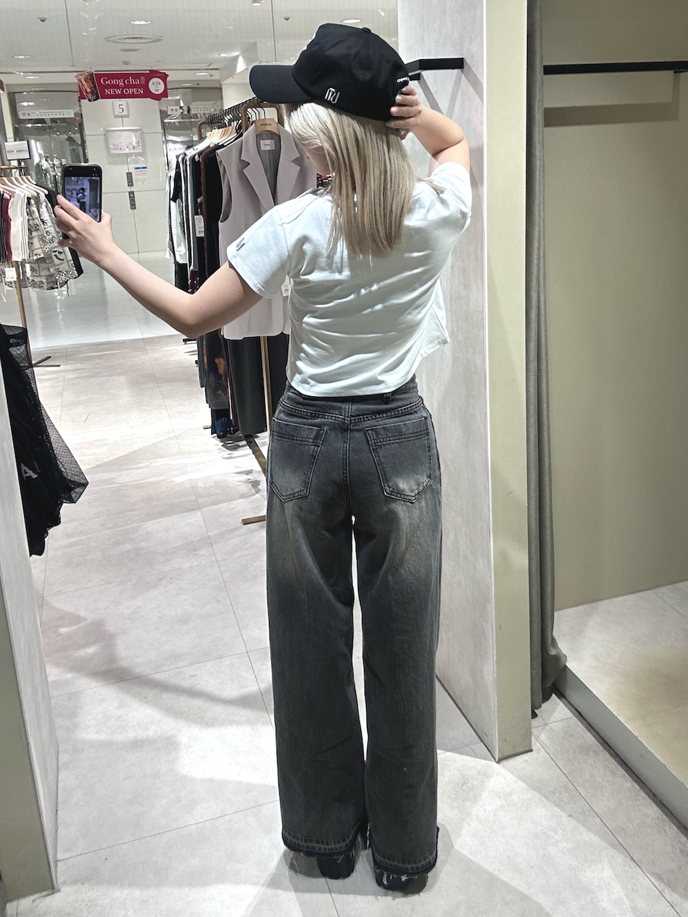 ブラック系のデニムパンツ、ブラック系のブーツ、ホワイト系のTシャツ/カットソーを着用したレディースの春コーディネートの4枚目の写真