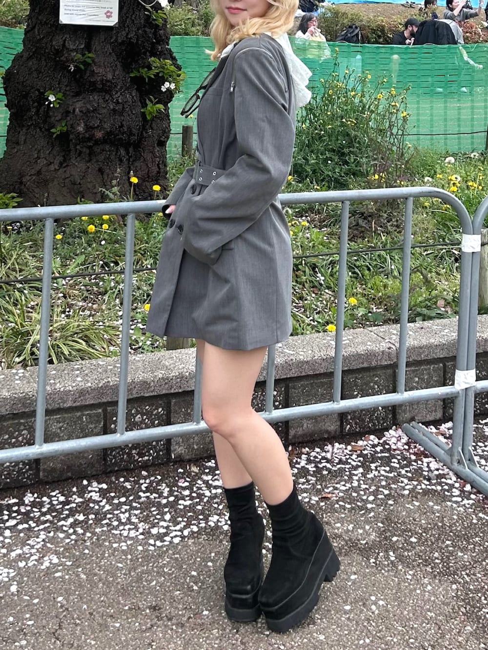 グレー系のテーラードジャケット、ホワイト系のパーカー、ブラック系のブーツを着用したレディースの春コーディネートの2枚目の写真