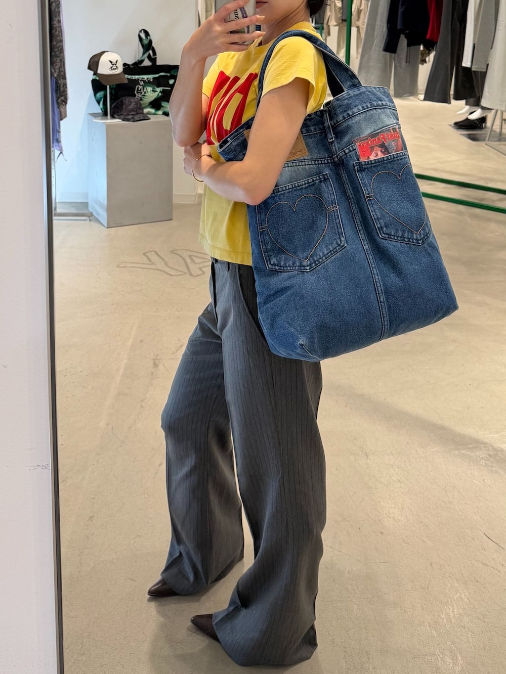 グレー系のスラックス、イエロー系のTシャツ/カットソー、ブルー系のトートバッグを着用したレディースの秋コーディネートの2枚目の写真
