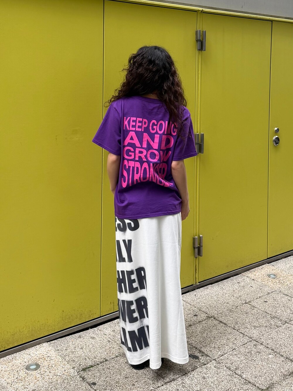 パープル系のTシャツ/カットソー、ホワイト系のスカート、グレー系のその他小物を着用したレディースの春コーディネートの2枚目の写真
