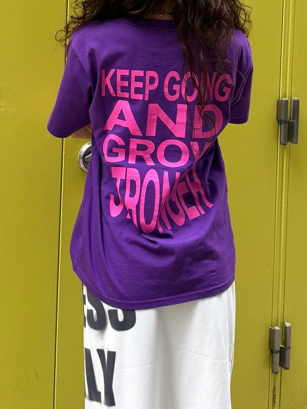 パープル系のTシャツ/カットソー、ホワイト系のスカート、グレー系のその他小物を着用したレディースの春コーディネートの4枚目の写真