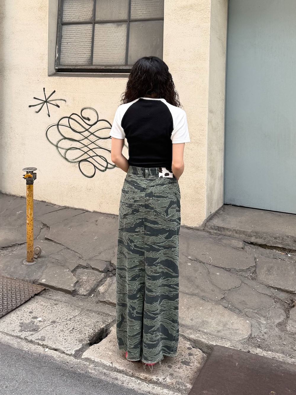 グリーン系のスカート、ブラック系のTシャツ/カットソー、ピンク系のサンダルを着用したレディースの春コーディネートの3枚目の写真