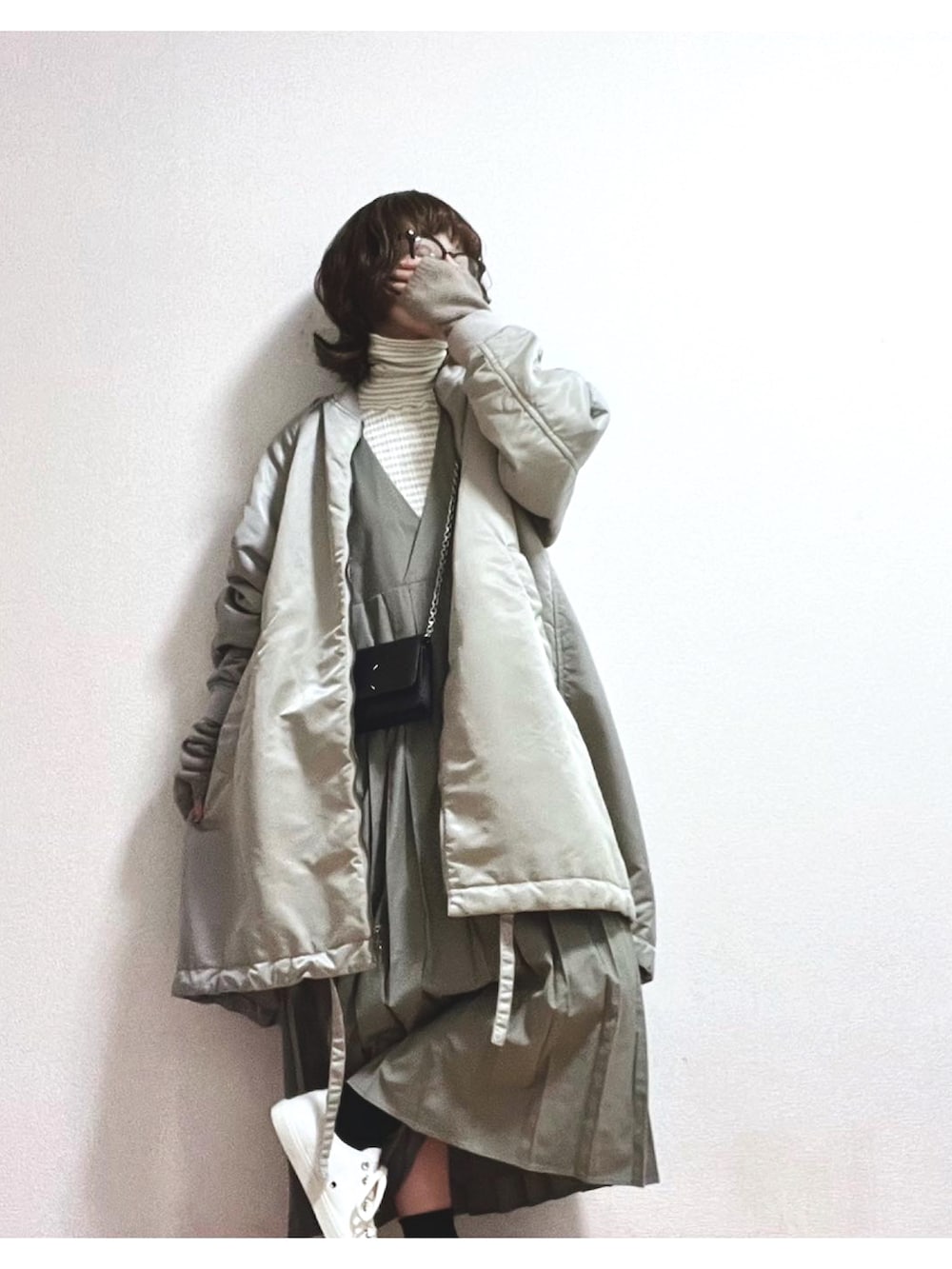 グリーン系のジャンパースカート、ブラック系のスニーカー、ブラック系の財布を着用したレディースの冬コーディネートの2枚目の写真