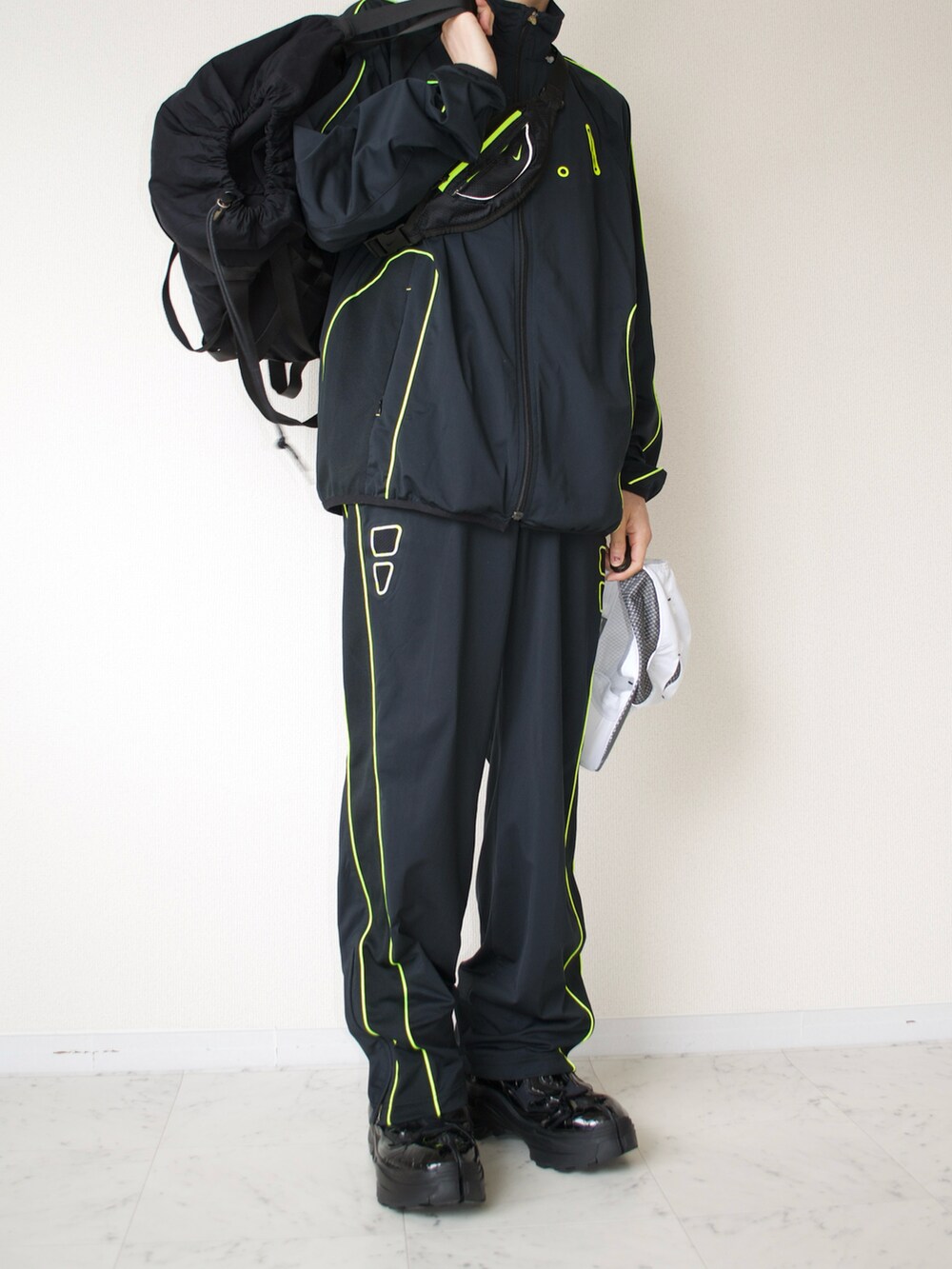 ブラック系のジャージ、ブラック系のパンツ、ブラック系のバックパック/リュックを着用したメンズの春コーディネートの2枚目の写真