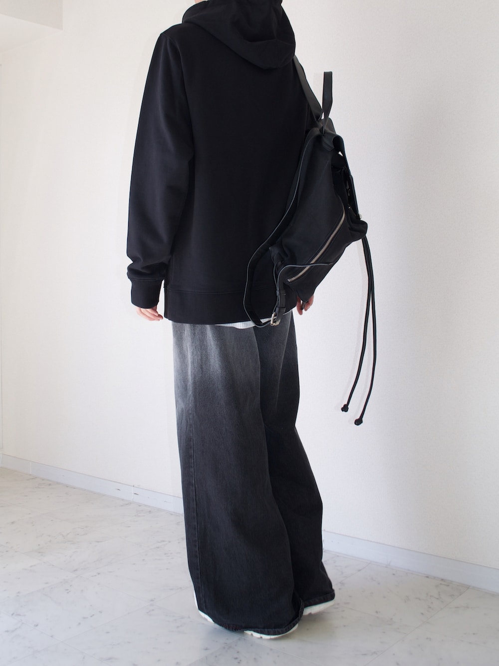ブラック系のパーカー、ブラック系のデニムパンツ、ブラック系のバッグを着用したメンズの秋コーディネートの2枚目の写真