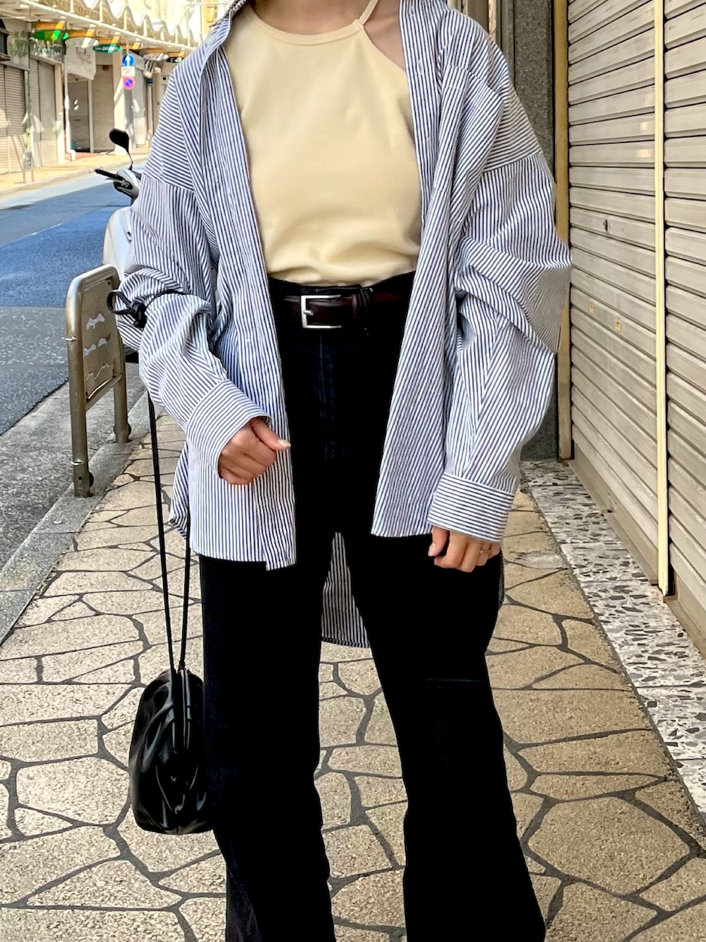 ブラック系のスニーカー、ブルー系のデニムパンツ、ベージュ系のキャミソールを着用したレディースの春コーディネートの2枚目の写真