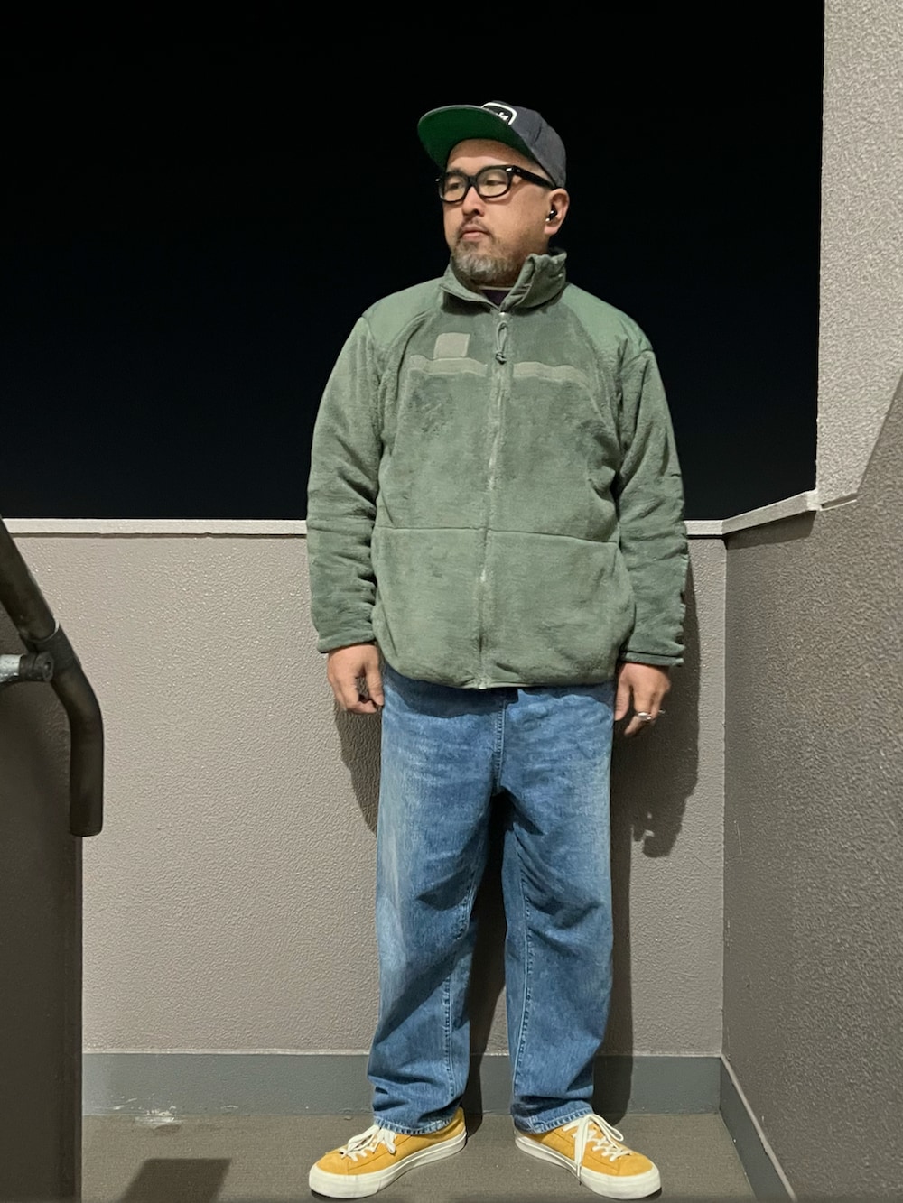 ブルー系のデニムパンツ、グリーン系のミリタリージャケット、パープル系のTシャツ/カットソーを着用したメンズの春コーディネートの2枚目の写真