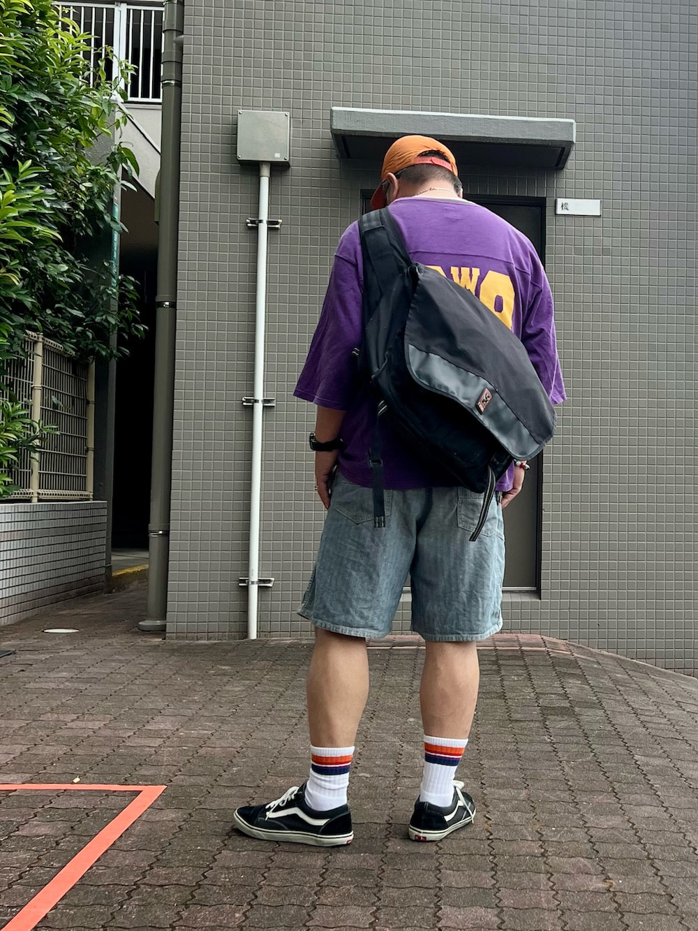 ブラック系のスニーカー、パープル系のTシャツ/カットソー、ブルー系のデニムパンツを着用したメンズの秋コーディネートの2枚目の写真