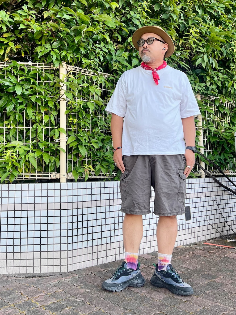 ホワイト系のTシャツ/カットソー、グレー系のカーゴパンツ、ブラック系のスニーカーを着用したメンズの夏コーディネートの2枚目の写真