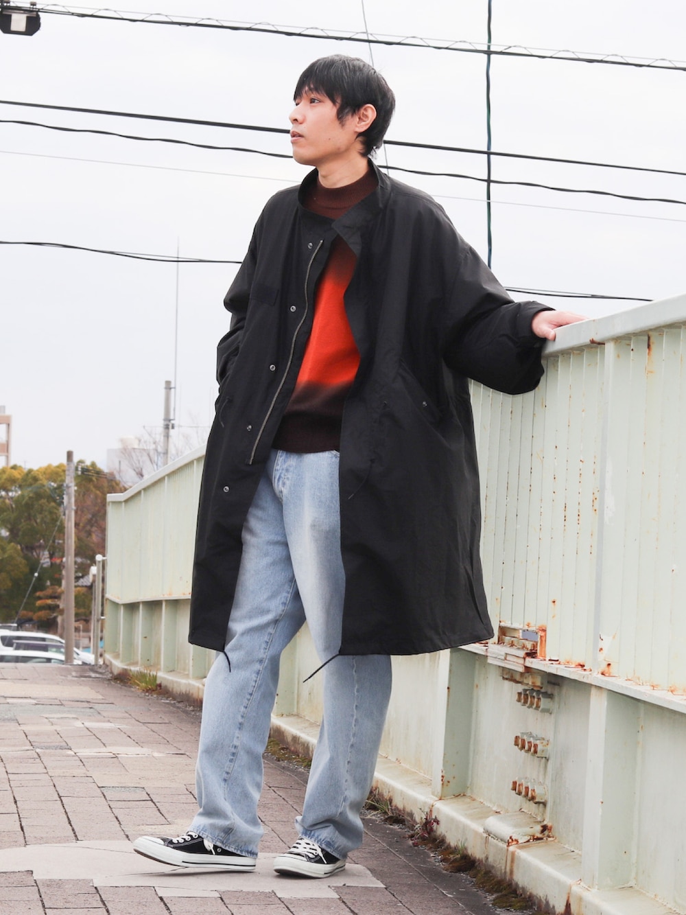 ブラック系のモッズコート、ブルー系のデニムパンツ、ブラック系のスニーカーを着用したメンズの冬コーディネートの2枚目の写真