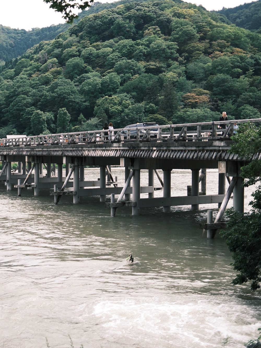 ブルー系のTシャツ/カットソー、ブラック系のショルダーバッグ、ブルー系のデニムパンツを着用したメンズの夏コーディネートの2枚目の写真